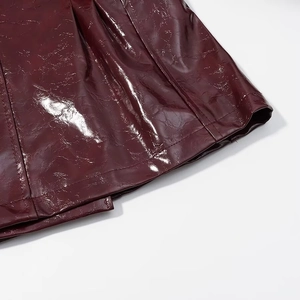 Dettaglio dell'orlo della gonna in ecopelle rosso vino lucido con cuciture di pregio