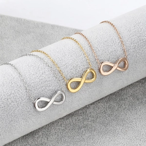 Primer plano de collares de símbolo infinito en plata, oro y oro rosa en un rollo