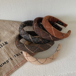 Close-up of four thick knitted plaid headbands in beige brown and grey colors