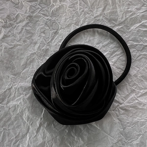 Detail of elegant black rose hair tie on a textured white paper background