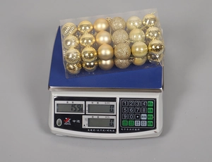 Detailed view of a 24-piece gold Christmas ball set weighing 159g on a digital scale