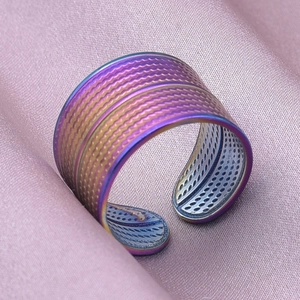 Macro detail of rainbow stainless steel adjustable ring with woven texture on silk