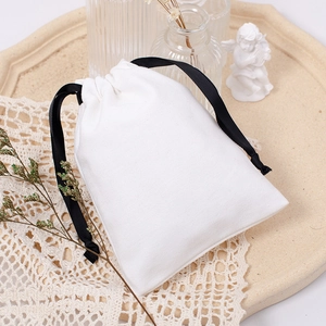 Detailed view of a white canvas drawstring pouch with lace and floral decorations