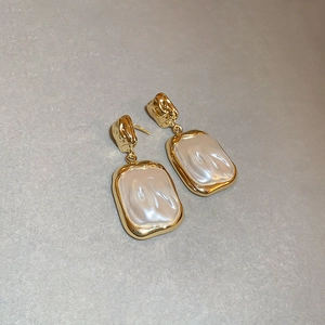 Detail of vintage hammered gold earrings featuring baroque imitation rectangular pearls