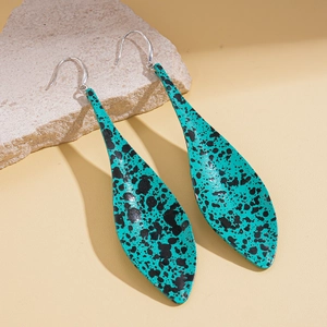 Detailed view of turquoise leaf drop earrings with black splatter on stone