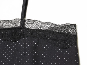 Détail du décolleté en dentelle et des bretelles fines sur le haut noir à pois blancs