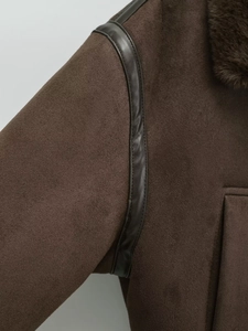 Detailed close-up of brown suede fabric with contrast black leather piping and faux fur lining