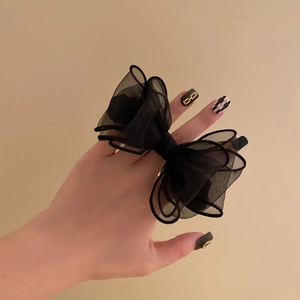Detail of a large black organza bow scrunchie showing the sheer mesh fabric and delicate edging