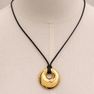Golden hollow circle pendant necklace with black cord shown on model neck closeup