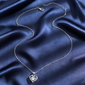 Sparkling silver heart pendant necklace with round zircon on dark blue silk backdrop