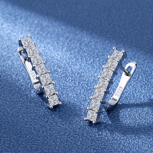 Macro shot of silver S925 earrings with square zircon stones on a blue background