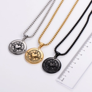 Close-up of heart compass pendants in silver, gold, and black with size reference ruler