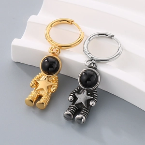 Close-up of gold and silver astronaut pendant earrings on a white stone pedestal