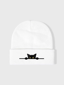 Dettaglio del berretto in maglia bianca con ricamo di gatto nero sul bordo risvoltato morbido