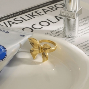 Detailed view of polished gold butterfly ring styled with luxury cosmetics on a white tray