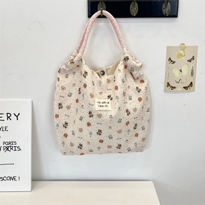Close-up of cream canvas tote bag with cartoon bear prints and braided rope handles