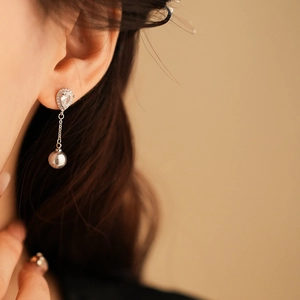 Detail of silver drop earrings with diamonds and pearls worn by a model