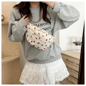 Close-up of white waist bag with red strawberry pattern worn as a crossbody chest pack