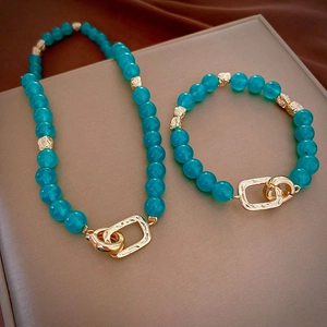 Detail view of turquoise beaded necklace and bracelet set with textured gold metal accents