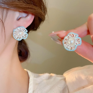 Detailed close-up of hollow flower pearl studs with light blue enamel and silver pins