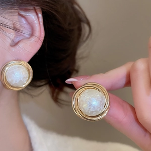 Detail of gold-plated geometric pearl earrings with textured white pearl inlay