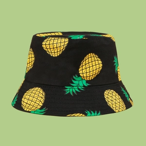 Detailed close-up of a black cotton bucket hat featuring a vibrant tropical pineapple print