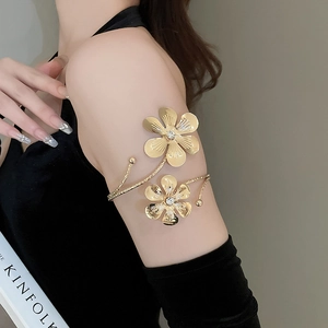Detail of adjustable gold flower arm cuff with matte finish and sparkling crystals