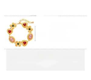 Detail view of gold vintage bracelet with red heart rhinestone and cameo portrait charm