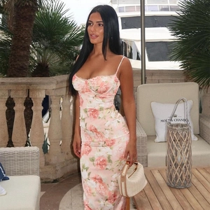 Pink floral print midi dress with corset style bodice and slit on an outdoor terrace