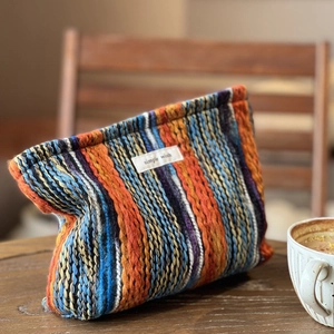 Gestreifte Strickhandtasche im Boho-Stil mit bunten Webmustern auf rustikalem Holztisch