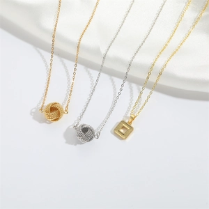 Detailed shot of gold and silver woven ball pendants on delicate chains over white silk