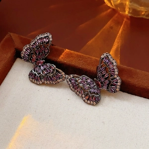 Detailed macro view of butterfly earrings with purple and white cubic zirconia stones