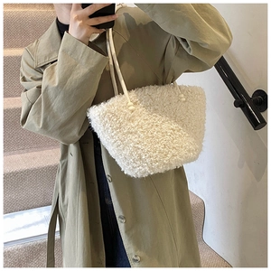 Gros plan d'un sac à main en peluche blanche douce avec poignée porté par un mannequin