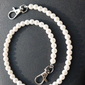 Detail of white faux pearl chain featuring silver metal lobster clasps on each end