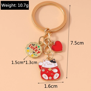 Detail view of lucky cat keychain with heart and biscuit charms on a pink background