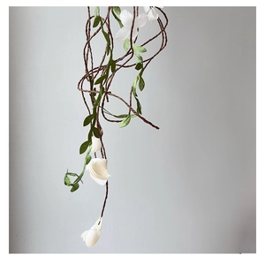 Detailed view of white tulip vine headband with artificial flowers and green leaves