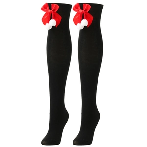 Detail of over-knee stockings with large red bow and white pom-poms on black knit fabric