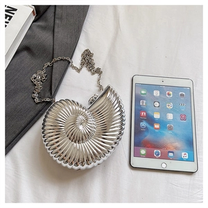 Detailed size comparison of silver snail shell clutch bag next to a tablet device