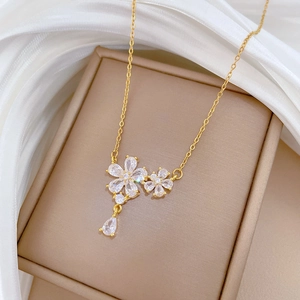 Detailed view of gold clover necklace with zircon crystals and drop pendant on silk
