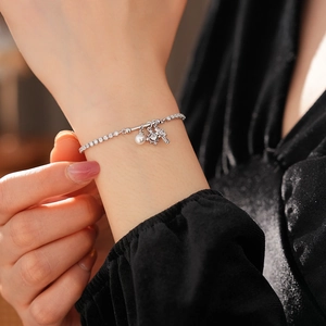 Detailed view of elegant silver bracelet with pearl, starburst, and cross charms on wrist