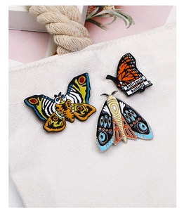 Three enamel butterfly pins attached to a canvas bag with Anti-Social Butterfly text