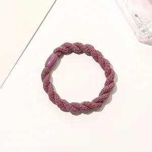 Detail of purple woven elastic hair tie with triple-strand braided texture and secure fastener