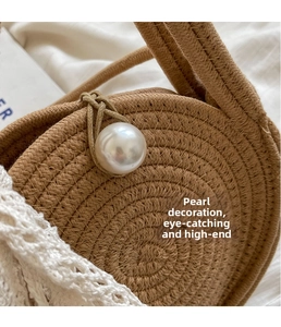 Detailed close-up of handmade straw bag with large pearl accent and white lace trim