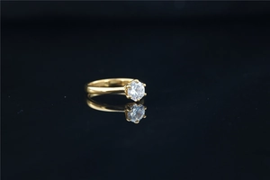 Detailed view of round brilliant-cut moissanite on gold titanium ring with black reflection