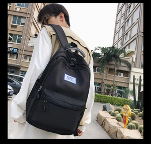 Detail of black nylon backpack featuring blue woven handle and durable shoulder straps