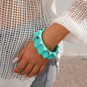 Detail shot of wavy turquoise resin bangle bracelet on female model wrist