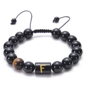 Close-up of black onyx bead bracelet with golden letter F and tiger eye stone detail