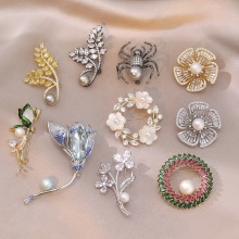 Detailed view of ten assorted retro metal brooches with pearls and rhinestones on silk