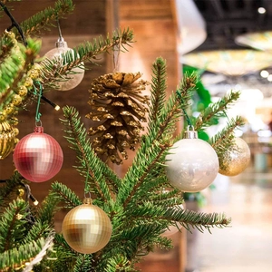 Close-up of red and gold Christmas ball ornaments and pinecones on a tree branch