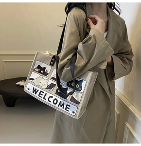 Detail shot of beige canvas cat tote bag featuring black handles and welcome print design